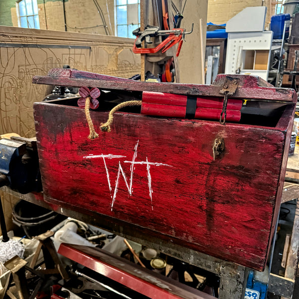 Red wooden box with 'TNT' marking in a workshop setting